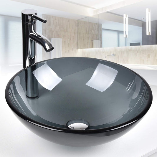 Close-up of black glass basin with faucet and drain on white countertop.