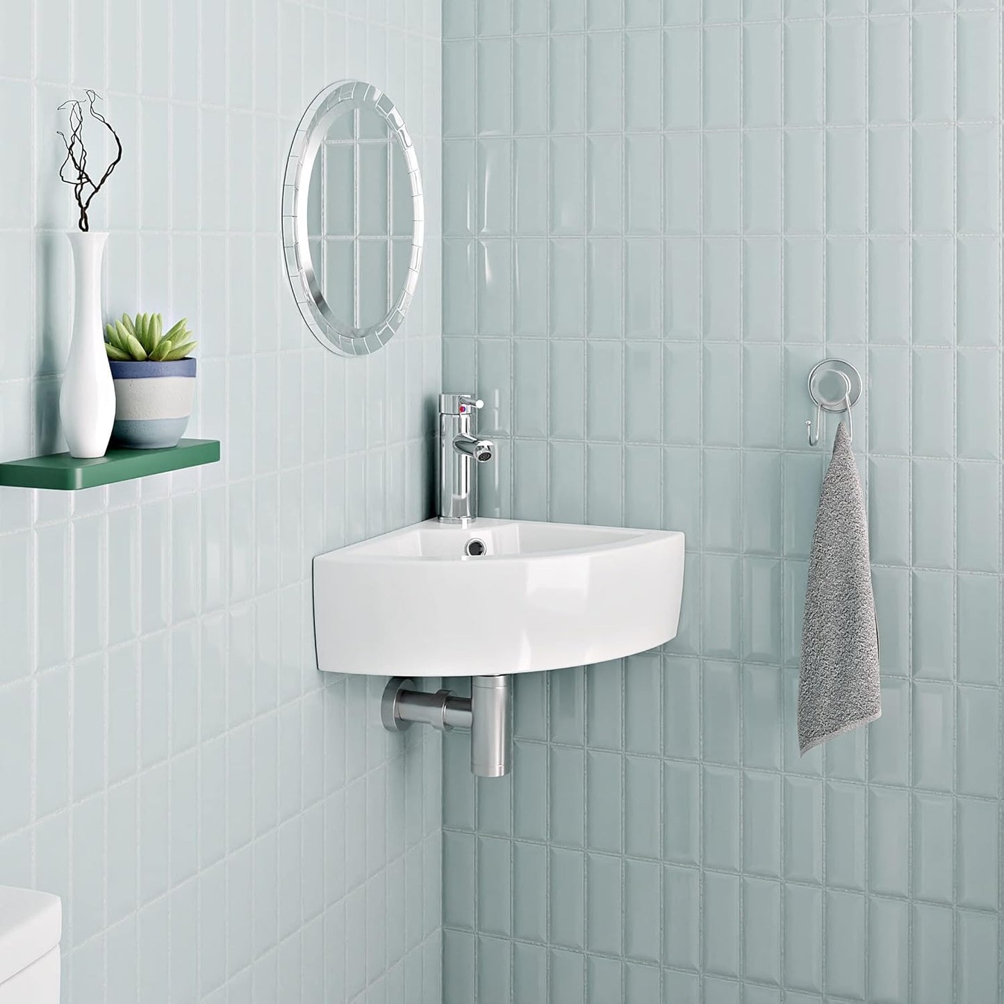 Compact white corner basin mounted in a modern bathroom with chrome tap.