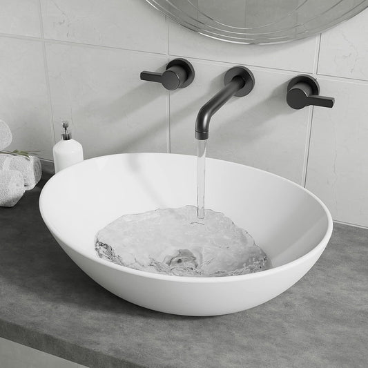 Gloss white oval counter top basin with water flowing from a black wall-mounted tap.