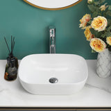 Gloss white rectangular counter top basin on a white countertop with gold decor and flowers.