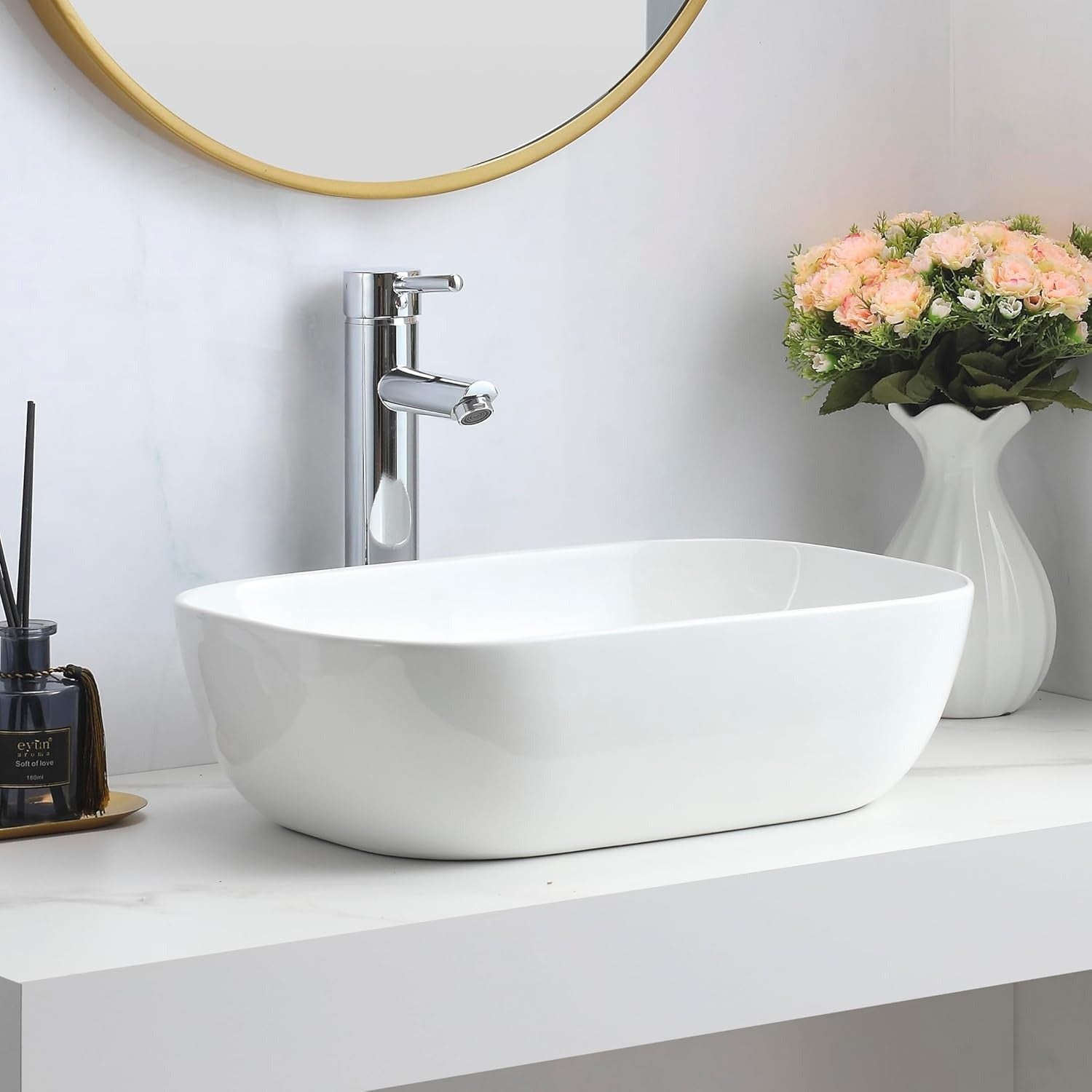 Gloss white rectangular counter top basin on a white vanity with a chrome tap and gold-framed mirror.