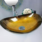 Oval gold glass basin with faucet and decorative mirror in bathroom.